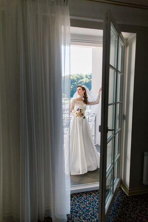 Gorgeous romantic bride in white dress and veil posing at hotel balcony.の写真素材