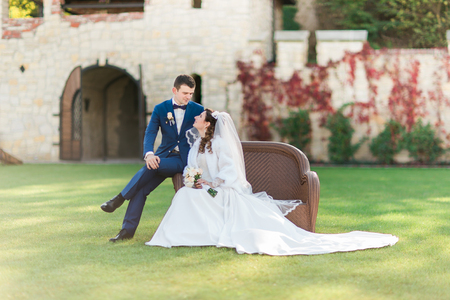 Beautiful bride and groom sitting on the wicker furniture outdoors.の写真素材