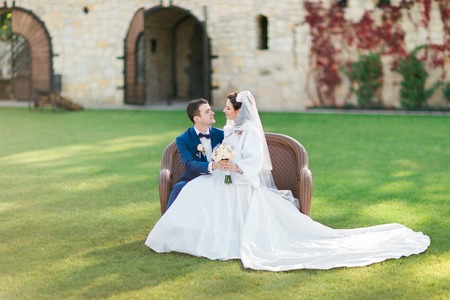 Beautiful bride and groom sitting on the wicker furniture outdoors.の写真素材