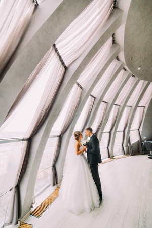 the couple are facing each other and embracing in a white roomの写真素材