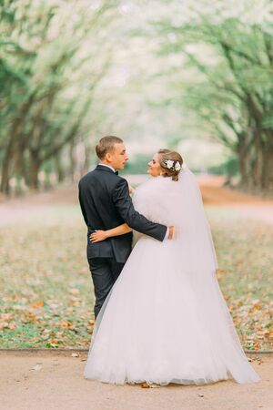 Beautiful groom and bride standing back on a forest background.の写真素材