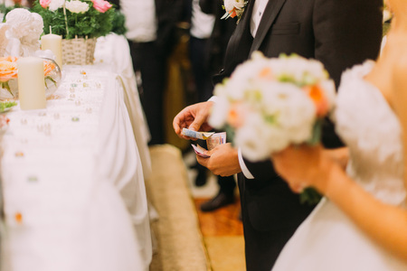 Handsome groom holding redemption of bride on wedding indoors.の写真素材