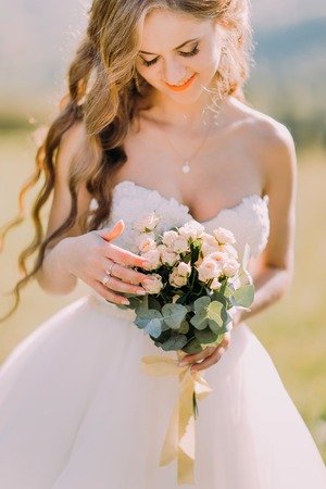 Gorgeous blond bride with wedding bouquet of pink roses close up.の写真素材