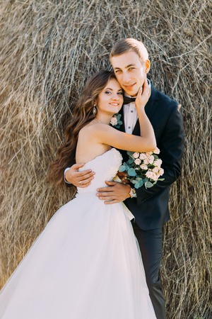 Close-up portrait of happy young married couple hugging on haystack.の写真素材