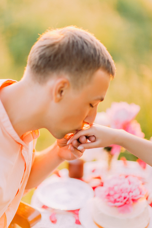 Outdoors portrait of young man proposing to girl with kiss on the hand, close-up.の写真素材