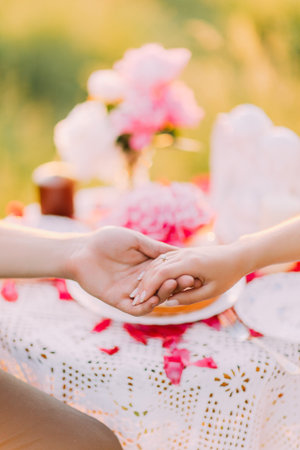 Women's hands with wedding rings close up. Hands on the table. lace sleeve dress, bouquet on brown book on the backgroundの写真素材