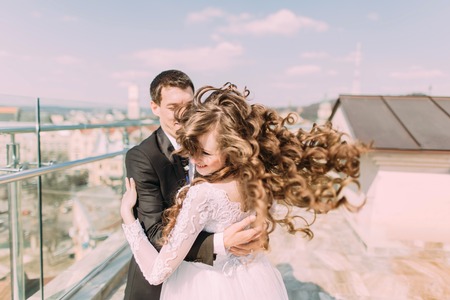 Photo of beautiful bride and groom dancing on roof top at sunny day.の写真素材