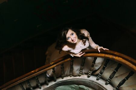 Stylish luxury bride in white dress posing on old wooden stairs, top view.の写真素材