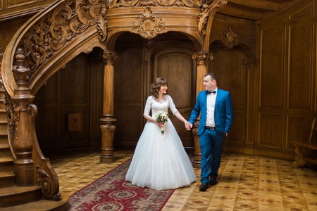 Beautiful bride and groom walking in the wooden hall of old theatre.の写真素材