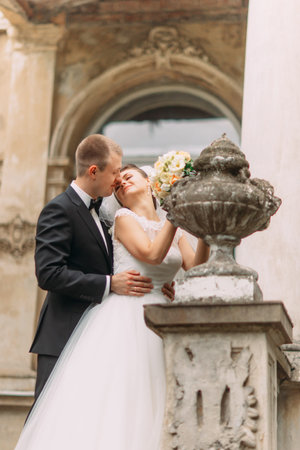 Cute married couple  touching noses close up standing on antique balcony with columns.