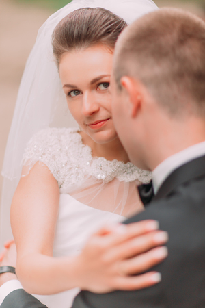 Portrait of beautiful bride looking at camera from behind the groom, close-upの写真素材