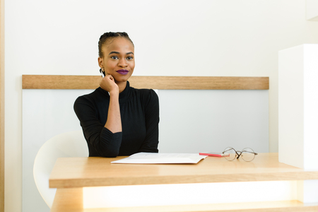 Thoughtful elegant African or black American businesswoman at desk in office.の写真素材