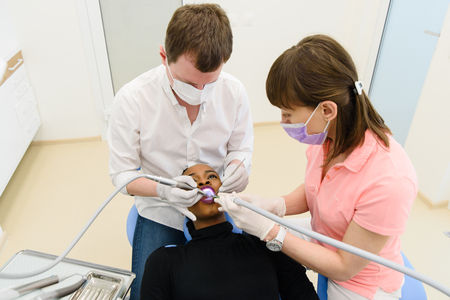 Dentist and nurse making professional teeth cleaning female young patient at the dental office.の写真素材
