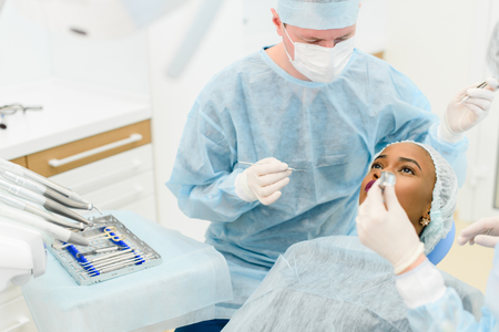 Dentist with assistant wearing medical uniforms making medical procedures female patient in scrup cup at the dental clinic.の写真素材
