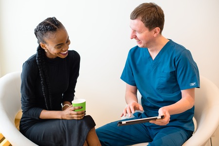 Smiling female patient and doctor have consultation in hospital room.の写真素材