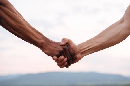 Close-up of mixed race couple holding hands on the misty mountain background.の写真素材