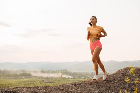 Full-length portrait of attractive brunette woman runner with perfect muscular body jogging outdoor...