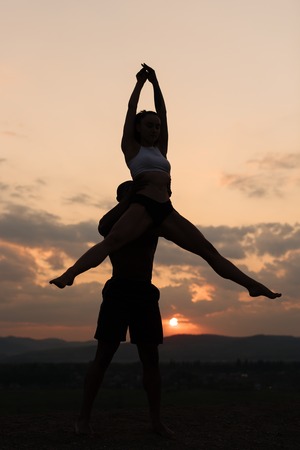 Silhouettes of beautiful mixed couple of gymnasts dancing on sunset. Grace and beauty of human's body.の写真素材