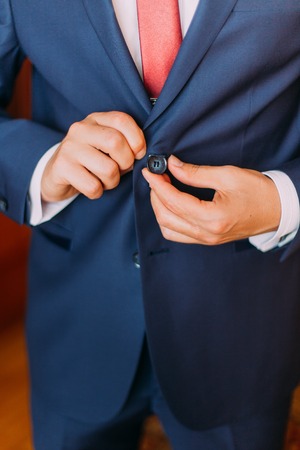 Handsome luxury dressed man in white shirt holding jacket over his forearm. Classic wooden room interior as background.の写真素材
