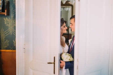 Loving newlywed bride and groom closing the doors while kissing.の写真素材