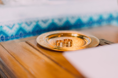 Pair of wedding rings on a golden salver with traditional slavic ornamented cloth at background.の写真素材