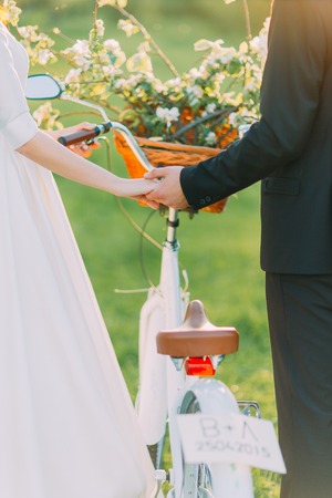 Romantic couple holding their hands in park with decorated bicycle between them.の写真素材