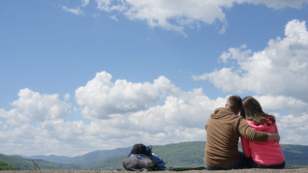 Moment of true happiness. Back view of loving tourist couple with backpacks embrasing  on the...