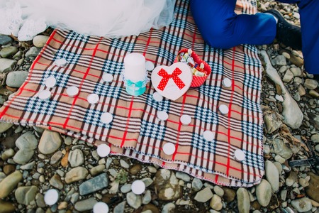 Romantic picnic on a river shore: tartan cloth, candles and box with candies.の写真素材