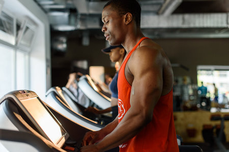 Black african american bodybuilder training on the treadmill in gym.