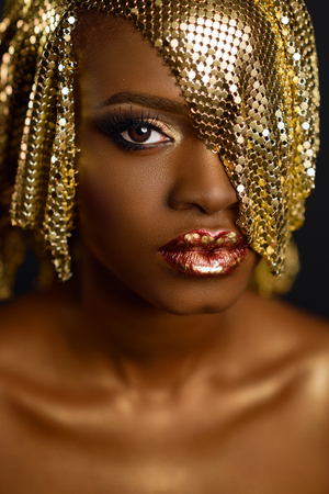 High fashion portrait of young african american female model with gold glossy makeup and hairstyle. Face artの写真素材
