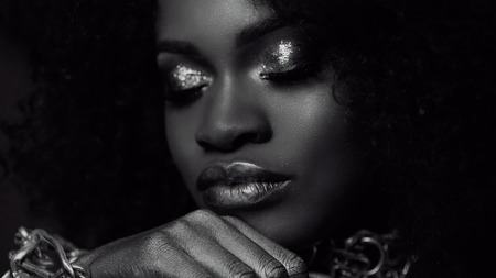 Surreal black and white close-up portrait of young african american female model with gold glossy makeup. Face art. Fashion concept.の写真素材