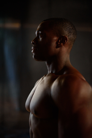 Male black african american fitness model showing muscles in studio with dark background.の写真素材