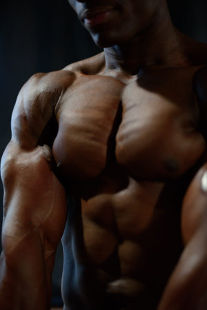 Close-up of african american man model naked torso posing and showing perfect body muscles in...