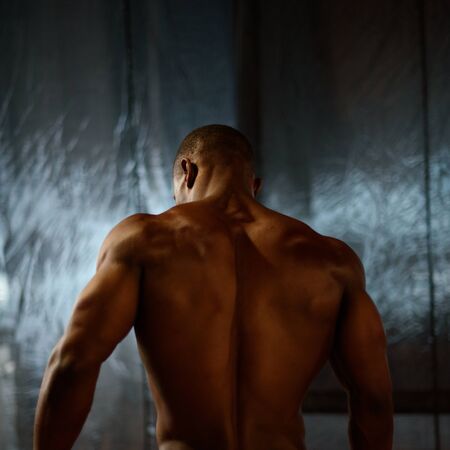 African american male body builder posing on a studio background. Back view.の写真素材