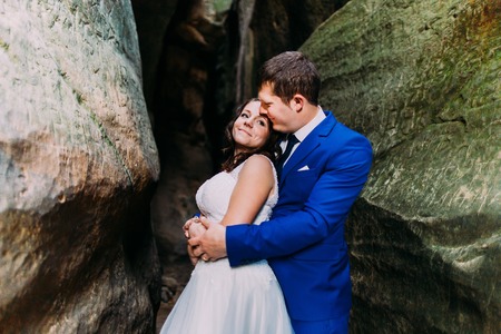 Young and romantic newlywed couple posing in weathered rock background.の写真素材