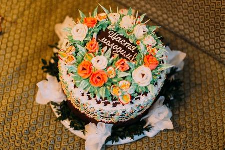 Chocolate cream cake with white and orange roses and holiday inscription.の写真素材