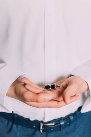 Two luxurious cufflinks in groom's hands. Close-up.の写真素材