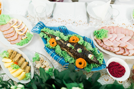 Beautifully decorated grilled fish with lot of different meat snacks on catering table.の写真素材