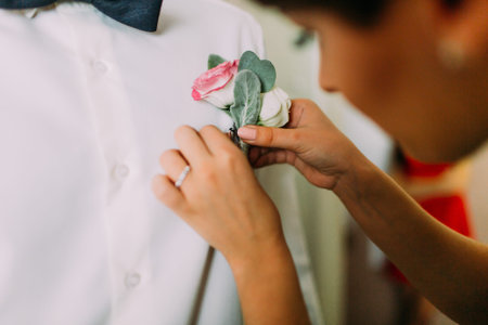 Wedding boutonniere and the hand of bride with ring.
