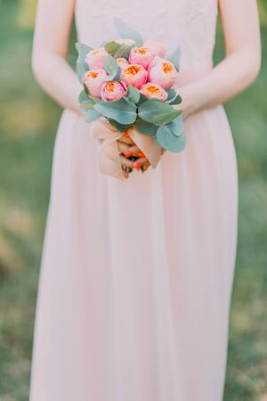 Nice wedding bouquet of purple, pink and white peonies hold by a bride in white dress.の写真素材