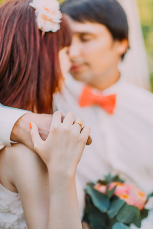 Pretty red-head bride looking at handsome groom holding his hand on her shoulder , close-up.の写真素材