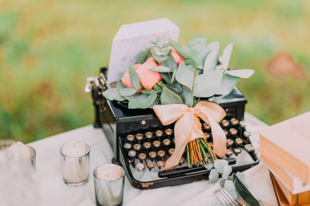 Vintage black typewriter and flowers on white table, outdoors.