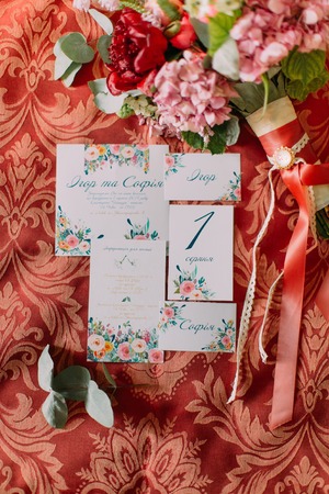 Top view of rose peonies with greenery with wedding invitations on red background.の写真素材