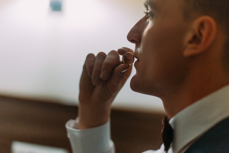 Young athletic man sitting in a hotel room on bed and kissing his wedding ring.の写真素材
