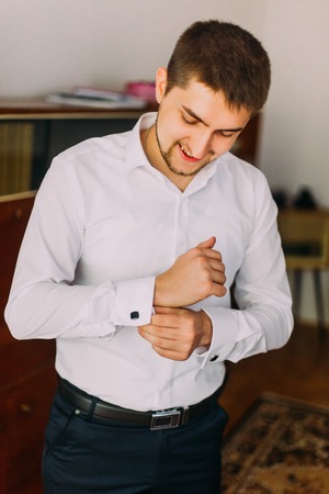 Elegant young fashion man attaching cufflinks to his white shirt.の写真素材