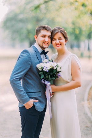 Elegant attractive bride and groom posing outdoors in the park. Newlyweds portrait shot.の写真素材