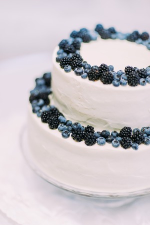 Candid cream cake decorated with bilberries and blackberries isolated close-up on white background.の写真素材