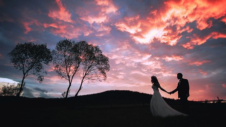 Silhouette of a loving couple against the evening pink sunset sky.の写真素材