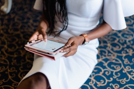 sexy body of black woman in white dress. she is taking a tablet in her hands chatting in internet....