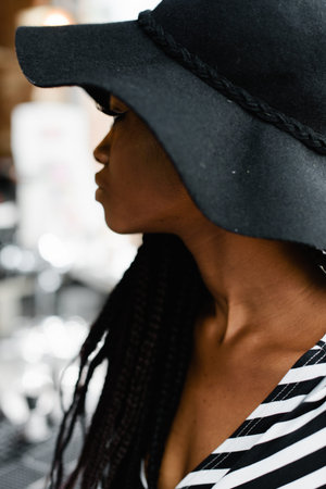 Close up photo of attractive american girl. Femine looking at someone. Model in black hat.の写真素材
